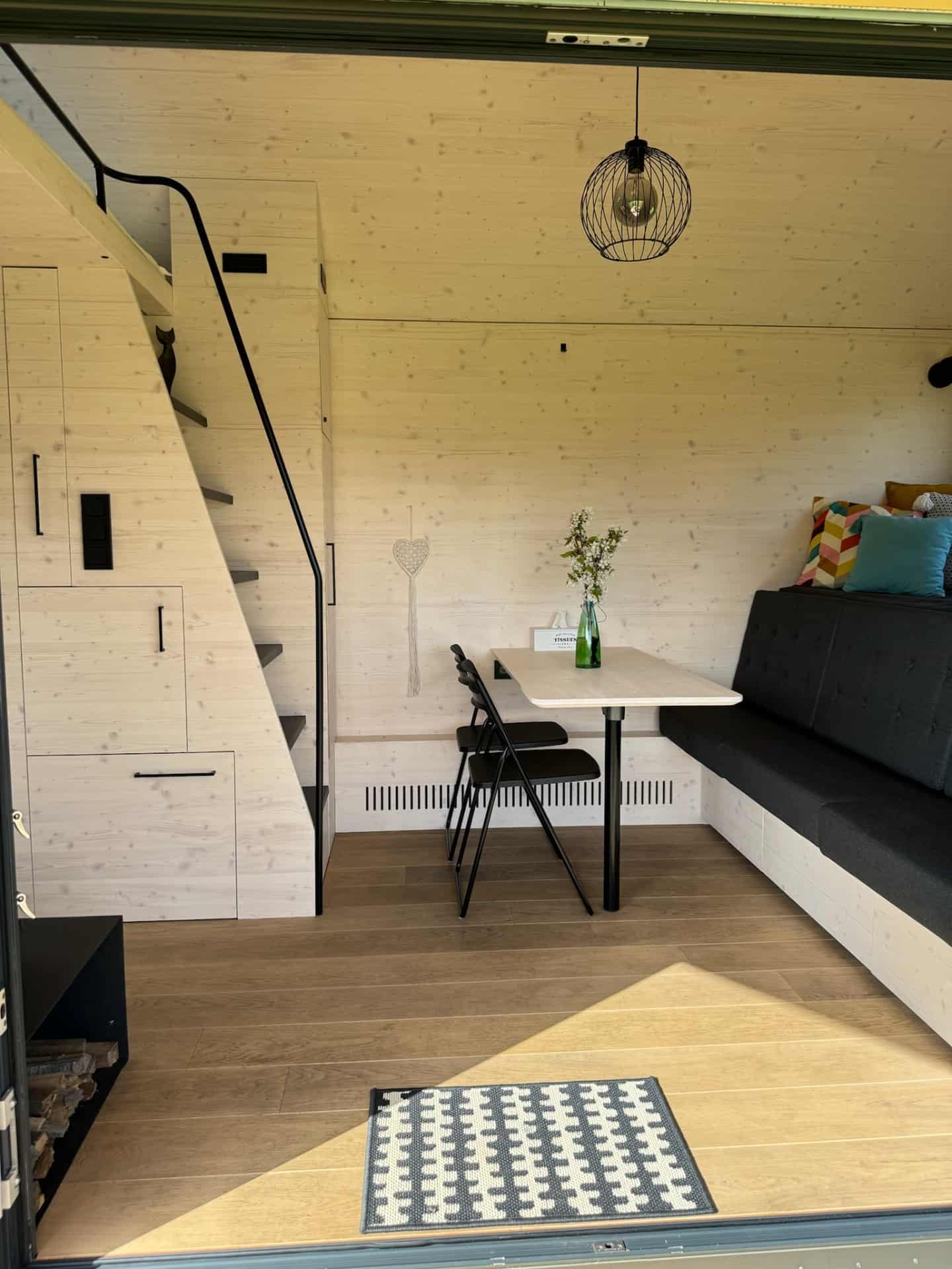 Entrance to tiny house Hutka — stairs to loft, stove and dining area